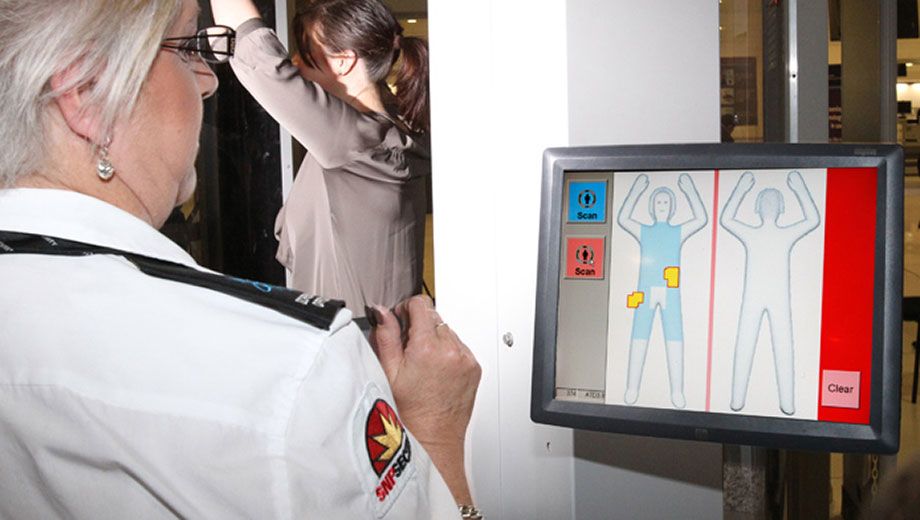A security guard watches as a passenger passes through a millimetre wave scanner at Sydney Airport during last month's trials