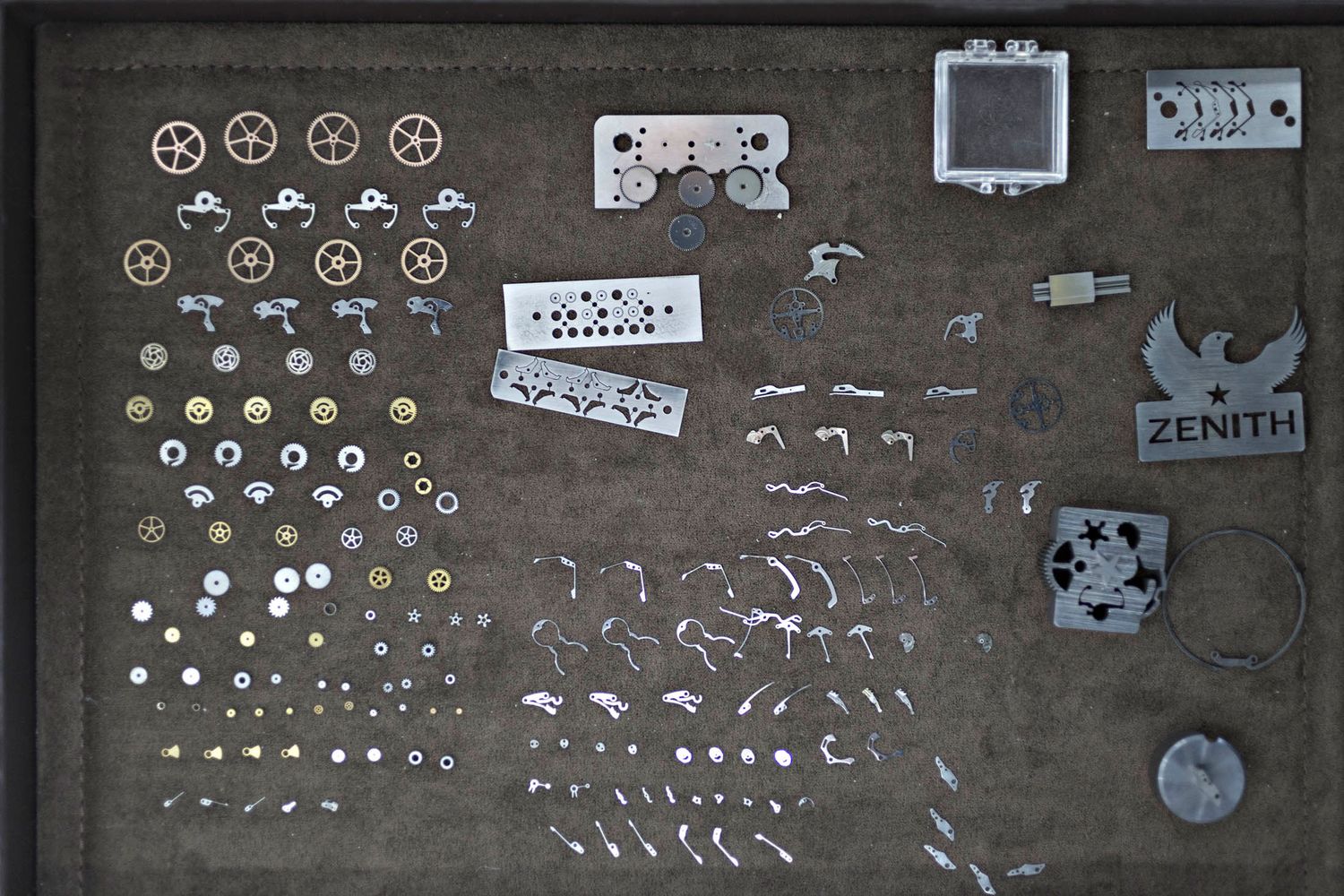 Wristwatch components sit ready for assembly. These tiny arms and balance wheels are all manually assembled by workers, using microscopic lenses in ultra-sterile workspaces.