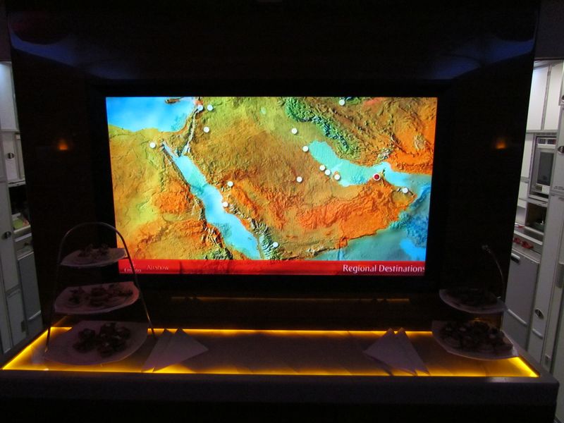 A big flatscreen monitor shows flight details and information about Emirates.