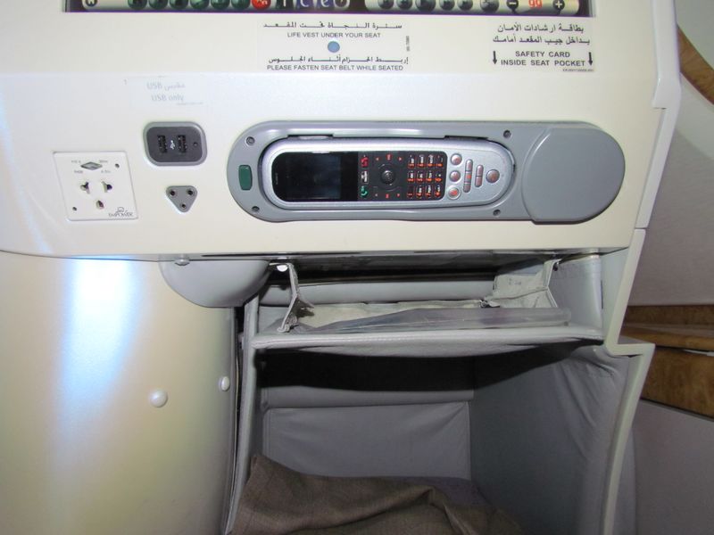 In front of you, the entertainment controls, in-flight power, and USB charging sockets sit below the entertainment screen, with the 