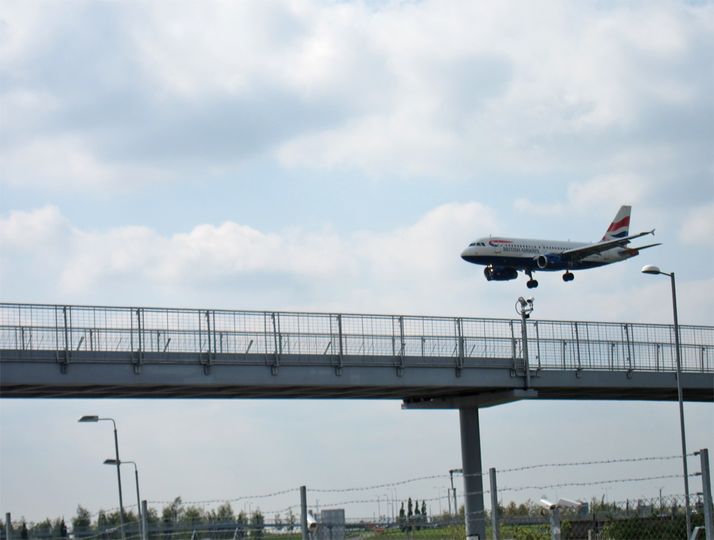 The pods roll over this elevated skyway, while planes land overhead.