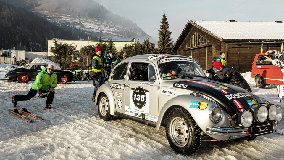 A skier limbers up behind a rally modded Volkswagen Bug ahead of the Skijoring 2WD classification race.