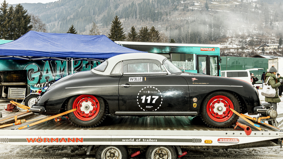 An ice-ready Porsche 356 Speedster with studded tires sits on a trailer between races.