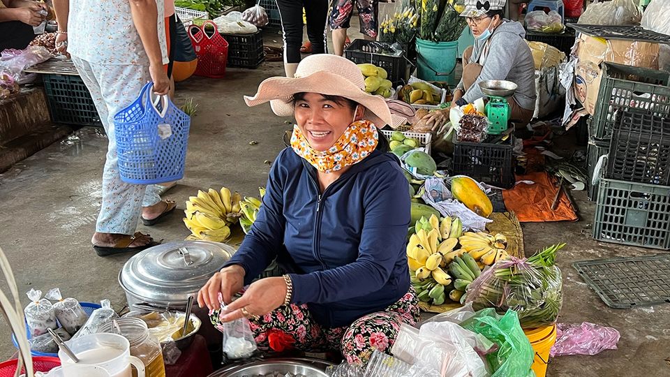 A Vietnamese landlady poses for a photo, before replacing her mask again.