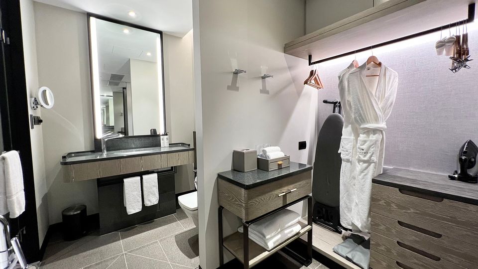The dressing area includes ample draw and hanging space, with an iron and mid-size ironing board.