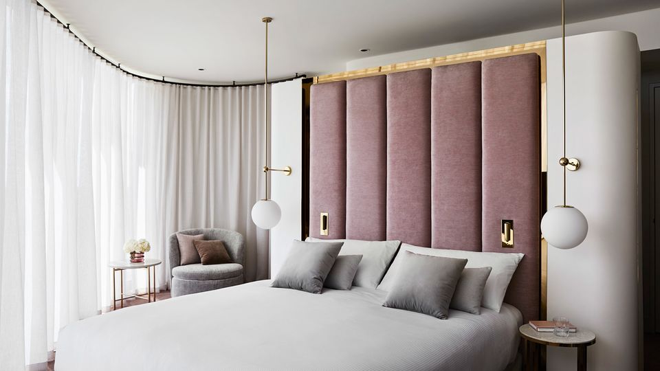 Deluxe Corner Room, furnished in warm shades of blush pink and gold.