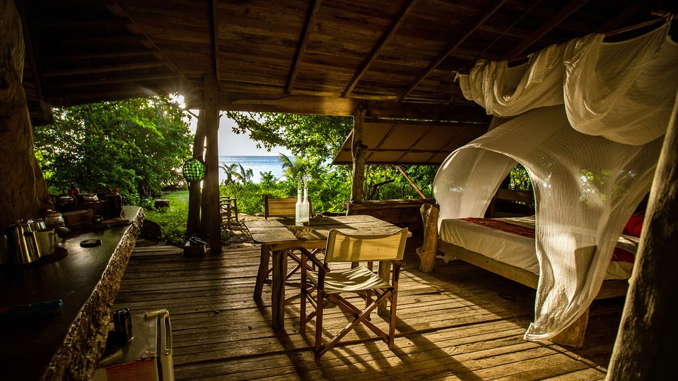 Canvas shutters open directly onto the sandy shoreline from the Beach Hut.