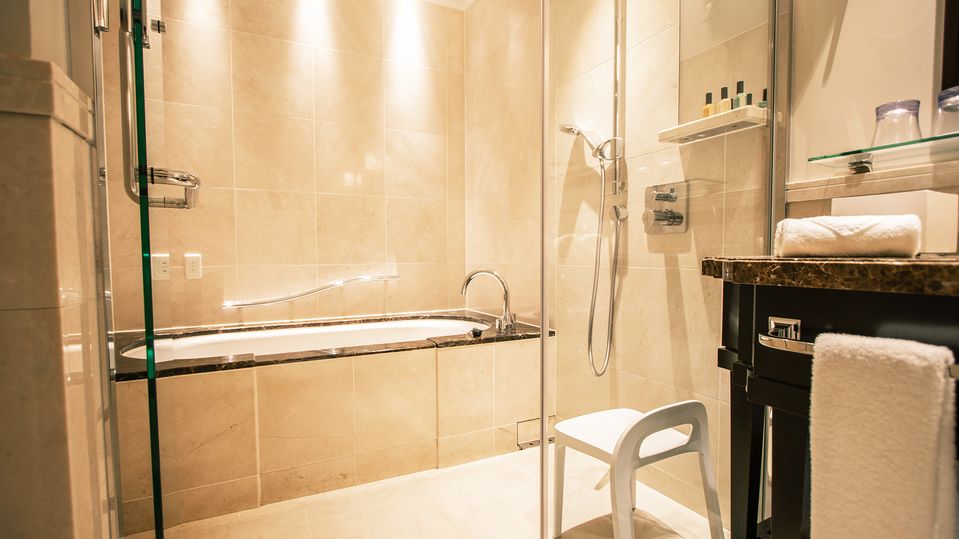 The shower and bathtub are both tucked behind a glass screen.
