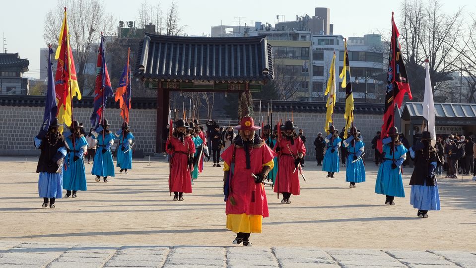 The captain of the guard flanked by soldiers and flag bearers.