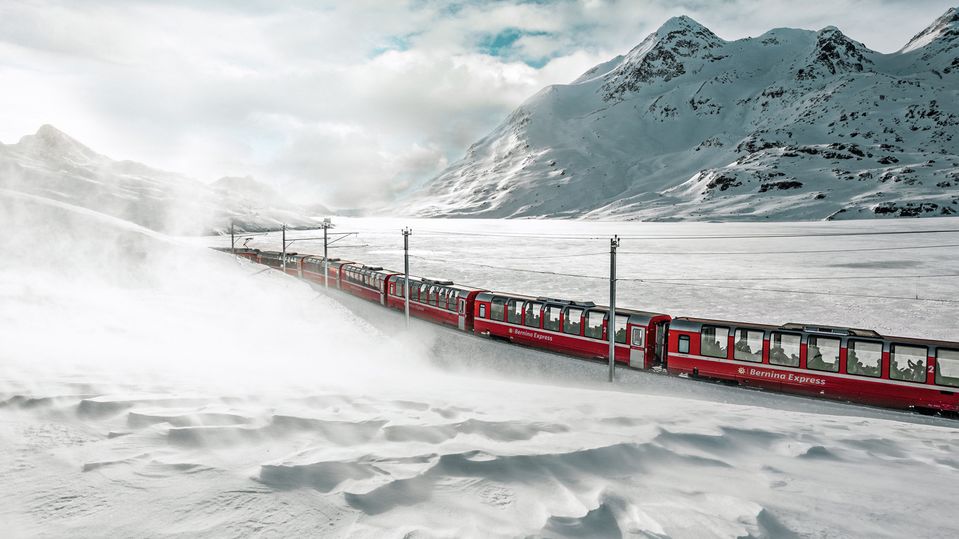Der Bernina Express fährt durch die winterliche Landschaft des Lago Bianco (Weißer See). Schweiz Tourismus