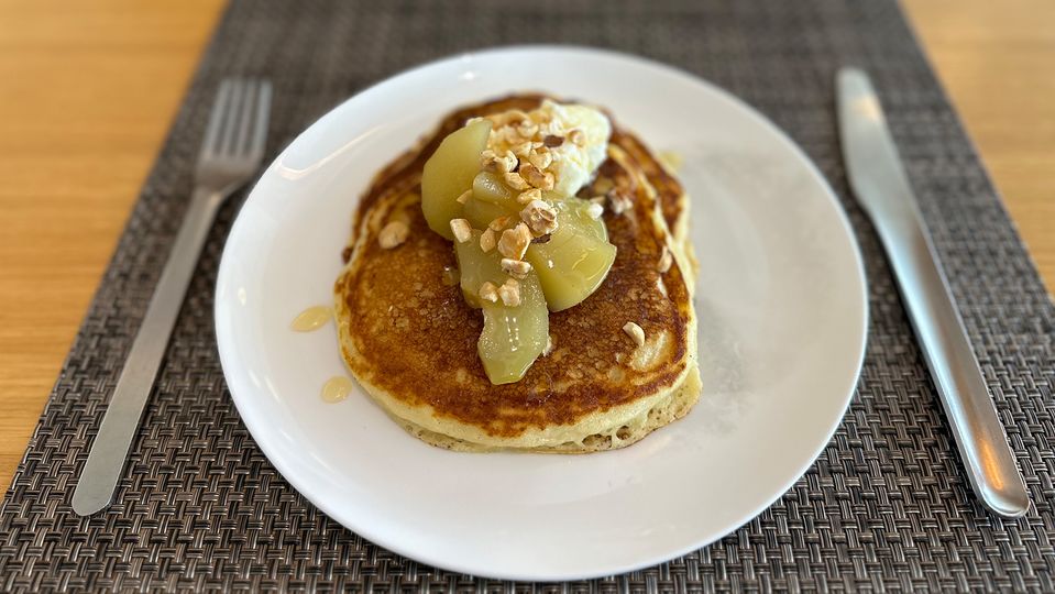 Buttermilk ricotta pancakes dressed with poached pears, hazelnuts and Qantas Honey.