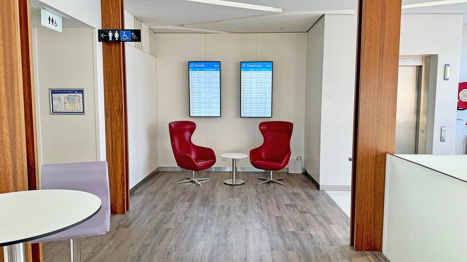 Departure and arrival screens are spaced throughout the lounge.